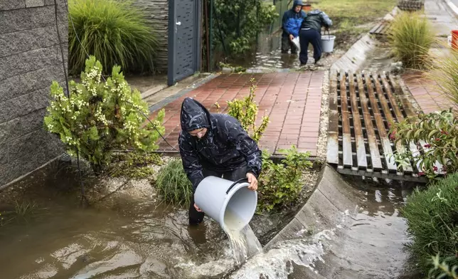 Residents bucket out water from their garden during floods in Zahorska Bystrica, Slovakia, Sunday, Sept. 15, 2024. (AP Photo/Tomas Hrivnak)