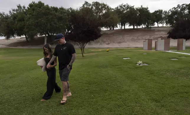 Mikayla Brown, left, and her husband, Tyler, hold hands as they walk toward their car after visiting the grave of their son, Elijah, who died of a fentanyl overdose at 15, in Paso Robles, Calif., Friday, Aug. 2, 2024. (AP Photo/Jae C. Hong)