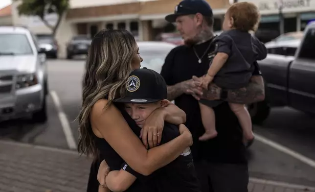 Mikayla Brown, left, comforts her son, Jax, as they stand in front of a park bench dedicated to her son, Elijah Ott, who died of a fentanyl overdose at 15, in Paso Robles, Calif., Friday, Aug. 2, 2024. (AP Photo/Jae C. Hong)