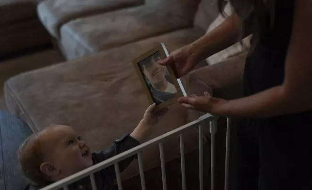 Mikayla Brown, right, shows a photo of Elijah Ott, who died of a fentanyl overdose at 15, to her youngest son, Crew, at their home in Atascadero, Calif., Friday, Aug. 2, 2024. (AP Photo/Jae C. Hong)