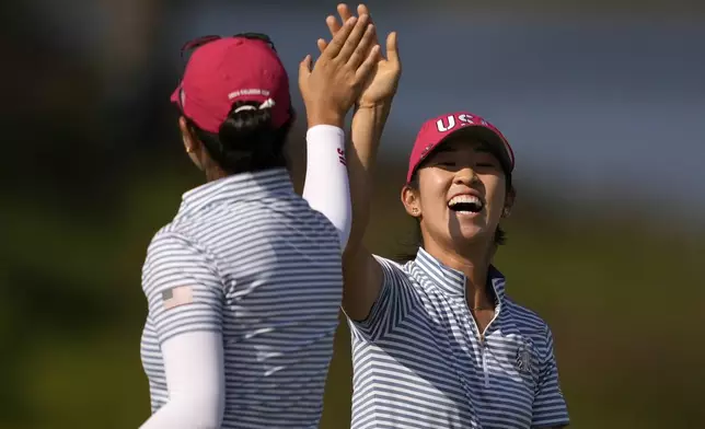 United States' Rose Zhang, right, is congratulated by teammate United States' Andrea Lee after hitting out of a bunker and into the cup on the 13th hole during a Solheim Cup golf tournament fourball match at Robert Trent Jones Golf Club, Saturday, Sept. 14, 2024, in Gainesville, Va. (AP Photo/Matt York)