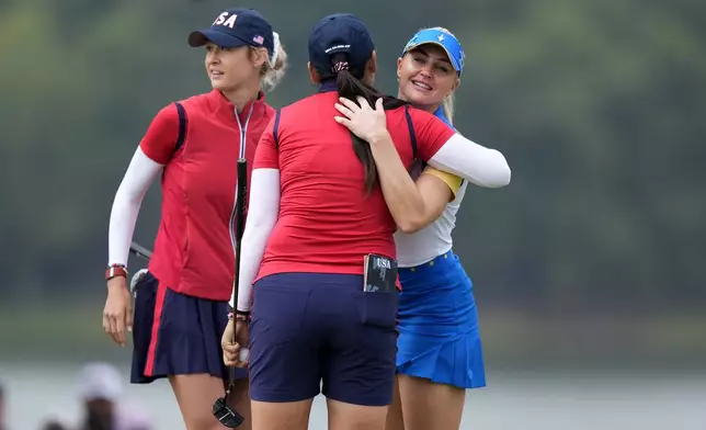 Europe's Charley Hull, right, congratulates United States' Allisen Corpuz, center, and Nelly Korda, left, on their win at the 16th hole during a Solheim Cup golf tournament foursomes match at Robert Trent Jones Golf Club, Friday, Sept. 13, 2024, in Gainesville, Va.(AP Photo/Chris Szagolo)