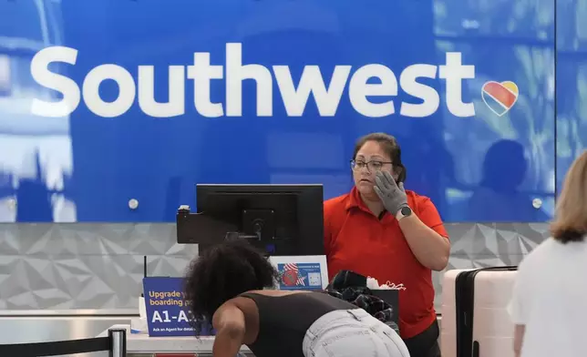 FILE - A Southwest Airlines ticket agent checks in passengers at Love Field in Dallas, July 25, 2024. (AP Photo/LM Otero, File)