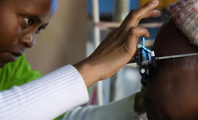 An optometry student, carries out an eye test on a patient for a new pair of glasses to be made, outside the Phelophepa eye clinic carriage in Tembisa, east of Johannesburg, South Africa, Thursday, Aug. 22, 2024. (AP Photo/Themba Hadebe)