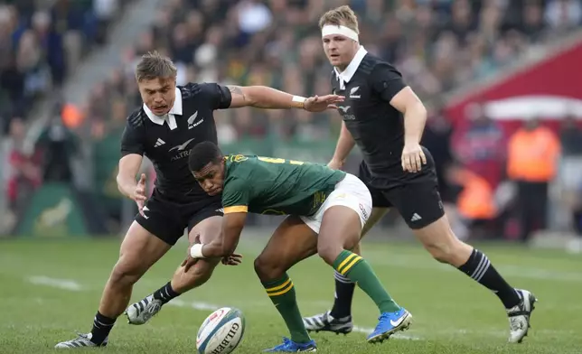 New Zealand's Cortez Ratima, left, and South Africa's Grant Williams, center, go for possession of the ball during a rugby championship test match between South Africa and New Zealand at Cape Town Stadium, South Africa, Saturday, Sept. 7, 2024. (AP Photo/Nardus Engelbrecht))