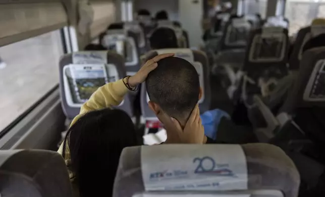 Kim Min-joo, left, feels the short haircut of her boyfriend, Kim Shin-hwa, on a train as they head to a Marine Corps induction ceremony in Pohang, South Korea, Monday, May 27, 2024. "As a South Korean man, I must enlist in military service at some point early in my life. No matter how frequently North Korea provokes or tensions rise, I cannot avoid my duty," said the recruit. (AP Photo/Jae C. Hong)