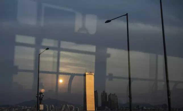 The 63 Building, once the tallest skyscraper in Asia, stands by the Han River, reflecting the light of the setting sun in Seoul, Wednesday, May 22, 2024. (AP Photo/Jae C. Hong)