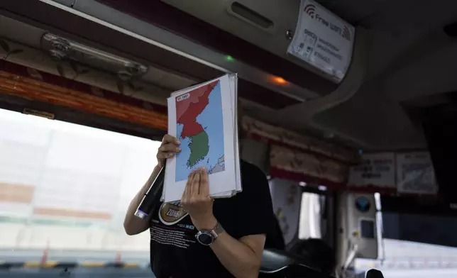 A tour guide holds a map while explaining the Korean War to tourists on a bus heading to Imjingak Pavilion in Paju, South Korea, Saturday, May 25, 2024. (AP Photo/Jae C. Hong)