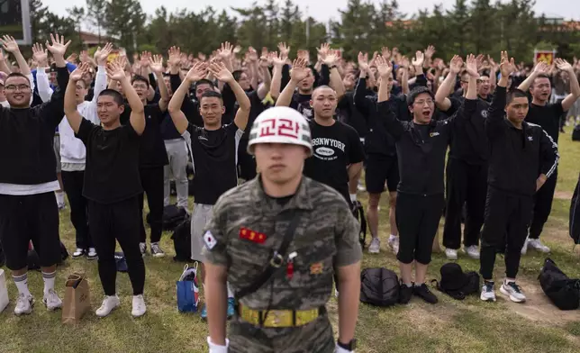 Standing behind a drill instructor, recruits wave to their family members during an induction ceremony at a Marine Corps base in Pohang, South Korea, Monday, May 27, 2024. In South Korea, military service is mandatory for most men. (AP Photo/Jae C. Hong)