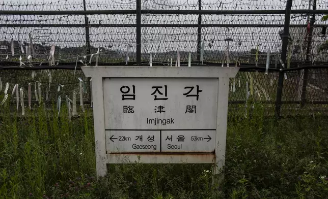 A directional sign showing the distance to North Korea's Kaesong and Seoul stands in front of fences adorned with ribbons bearing messages wishing for the reunification of the two Koreas at the Imjingak Pavilion in Paju, South Korea, Saturday, May 25, 2024. (AP Photo/Jae C. Hong)