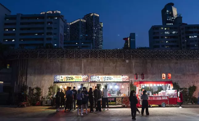 People form lines in front of food trucks at Yeouido Hangang Park, a popular destination for both residents and tourists, as dusk falls in Seoul, Wednesday, May 22, 2024. (AP Photo/Jae C. Hong)