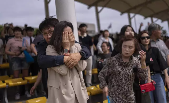 Yeon Soo Lee, 55, a kitchenware business owner from Gangneung, comforts his sobbing wife, Sun Young Kim, as they watch their son leave the training ground and head to his barracks after an induction ceremony at a Marine base in Pohang, South Korea, Monday, May 27, 2024. (AP Photo/Jae C. Hong)