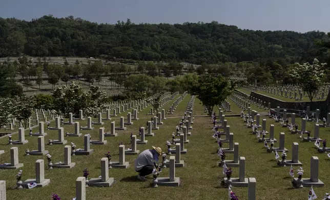 A worker places small South Korean flags at the graves of Korean soldiers who died in the Korean War ahead of Memorial Day at Seoul National Cemetery in Seoul, Thursday, May 23, 2024. (AP Photo/Jae C. Hong)