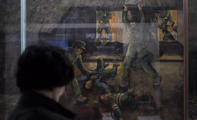 A visitor looks at a painting that depicts the murder of Lee Seung-bok and his family by North Korean infiltrators in 1968 at the Lee Seung-bok Memorial Hall in Pyeongchang, South Korea, Wednesday, May 22, 2024. (AP Photo/Jae C. Hong)