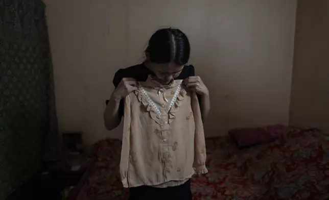 Yooree Kim holds up a blouse given to her by the adoption agency that sent her to France when she was 11 years old, at her apartment in Seoul, South Korea, Saturday, May 18, 2024. (AP Photo/Jae C. Hong)