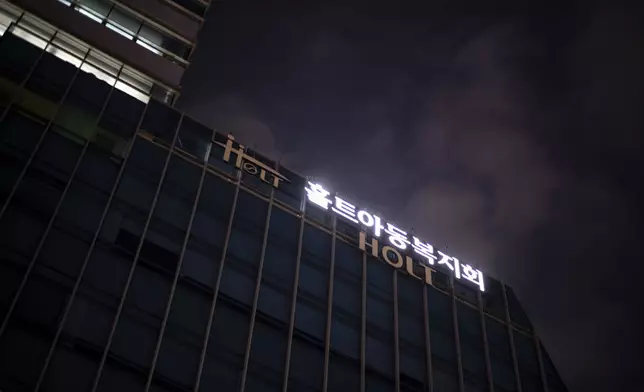 Signs for Holt Children's Services glow outside the company's office building at dusk in Seoul, South Korea, Friday, May 24, 2024. (AP Photo/Jae C. Hong)