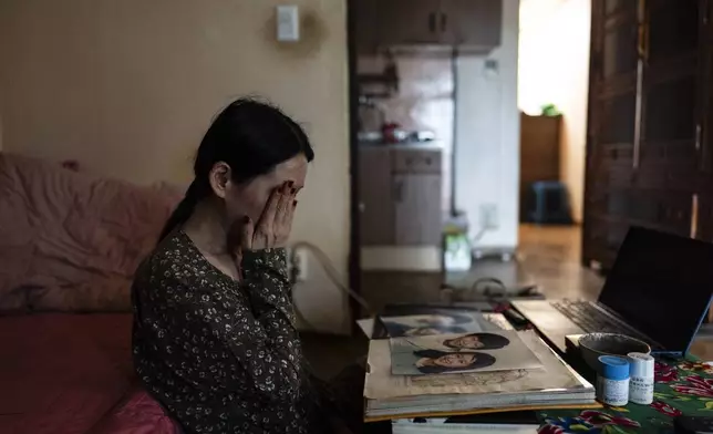 Yooree Kim, who was 11 when she and her brother were sent by the Korean adoption agency Holt Children's Services to a couple in France, looks over childhood photos in her apartment in Seoul, South Korea, Saturday, May 18, 2024. (AP Photo/Jae C. Hong)