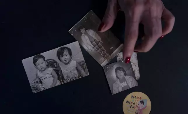 Yooree Kim, pictured at left, shows childhood photos of her and her brother, second from left, in her apartment in Seoul, South Korea, on Saturday, May 18, 2024, as she reflects on the adoption that sent them from South Korea to a French family when she was 11 years old. (AP Photo/Jae C. Hong)