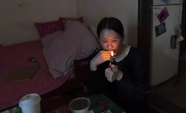 Yooree Kim, who is calling for an investigation into the adoption that sent her from South Korea to France at 11 years old, lights a cigarette in her apartment in Seoul, South Korea, Saturday, May 18, 2024. (AP Photo/Jae C. Hong)