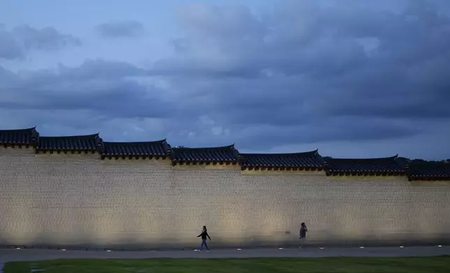 People walk along a wall outside the Gwanghwamun, one of South Korea's well-known landmarks, in downtown Seoul, South Korea, Friday, Sept. 27, 2024. (AP Photo/Lee Jin-man)