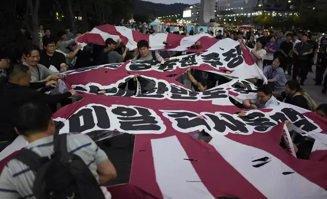 Protesters tear a huge banner as they oppose the meeting between South Korean President Yoon Suk Yeol and Japanese Prime Minister Fumio Kishida in Seoul, South Korea, Friday, Sept. 6, 2024. The part of banner reads "South Korea-U.S.-Japan military alliance." (AP Photo/Lee Jin-man)