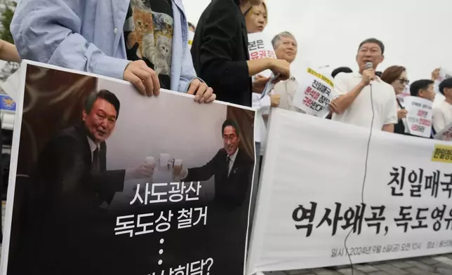 A protester holds a sign with a picture of South Korean President Yoon Suk Yeol, left, and Japanese Prime Minister Fumio Kishida during a rally opposing their planned meeting near the Presidential Office in Seoul, South Korea, Friday, Sept. 6, 2024. (AP Photo/Lee Jin-man)