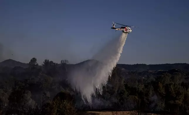 A Cal Fire Sikorsky S70i Firehawk helicopter performs a water drop on a hot spot during the Boyles fire in Clearlake, Calif., Sunday, Sept. 8, 2024. (Stephen Lam/San Francisco Chronicle via AP)