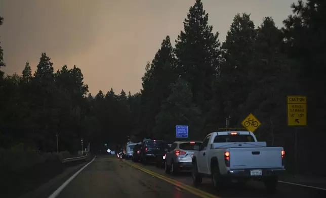 Motorists line up in the outskirts of town as smoke from the Line Fire fills the air Saturday, Sept. 7, 2024, in Running Springs, Calif. (AP Photo/Eric Thayer)