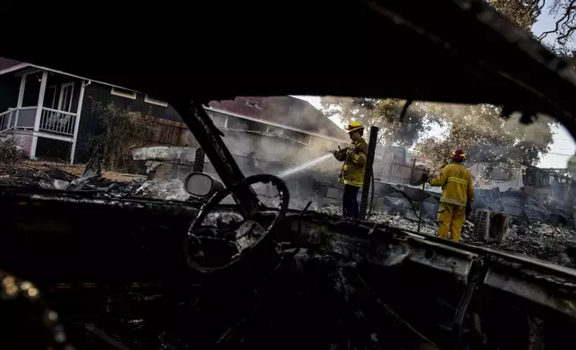 A Cal Fire firefighter puts water on a smoldering structure during the Boyles fire in Clearlake, Calif., Sunday, Sept. 8, 2024. (Stephen Lam/San Francisco Chronicle via AP)