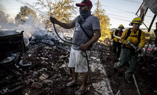 Gaudencio Ortiz douses water on a destroyed structure adjacent to his friend's home during the Boyles fire in Clearlake, Calif., Sunday, Sept. 8, 2024. (Stephen Lam/San Francisco Chronicle via AP)