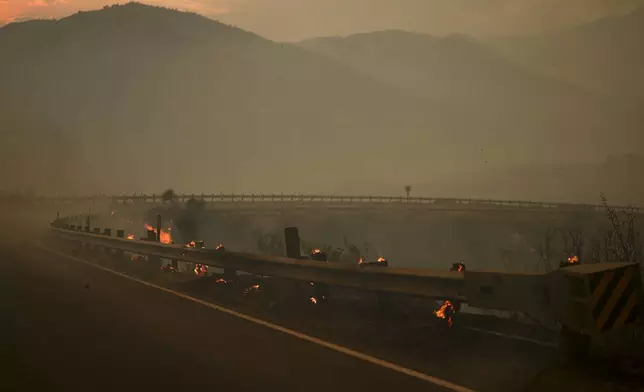 Wood posts along a railing on the side of a road smolders after the Line Fire swept through Saturday, Sept. 7, 2024, near Running Springs, Calif. (AP Photo/Eric Thayer)