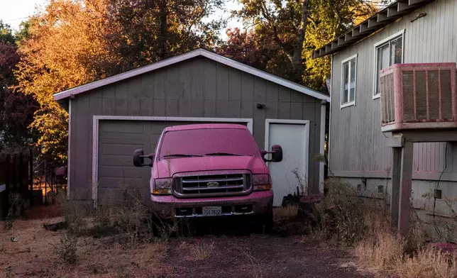 A car sits covered in fire retardant by a home during the Boyles fire in Clearlake, Calif., Sunday, Sept. 8, 2024. (Stephen Lam/San Francisco Chronicle via AP)