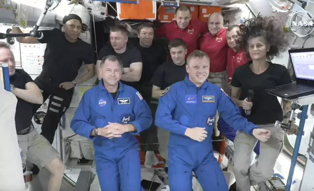 In this image made from a NASA livestream, the two astronauts stuck at the International Space Station since June 2024, Butch Wilmore, far left, and Suni Williams, far right, welcome two new residents who flew up on SpaceX, NASA's Nick Hague, front left in blue, and the Russian Space Agency's Alexander Gorbunov, front right in blue, Sunday, Sept. 29, 2024. Behind them, from left in black, are NASA's Jeanette Epps, Russia's Alexander Grebenkin, NASA's Mike Barratt and NASA's Matthew Dominick. From left, wearing red, are Russia's Ivan Vagner, NASA's Don Pettit and Russia's Alexei Ovchinin. (NASA via AP)