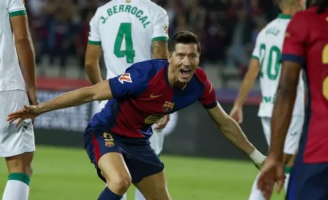 Barcelona's Robert Lewandowski, center, celebrates with Barcelona's Jules Kounde, front, after scoring the opening goal during a Spanish La Liga soccer match between Barcelona and Getafe at the Olympic stadium in Barcelona, Spain, Wednesday, Sept. 25, 2024. (AP Photo/Joan Monfort)
