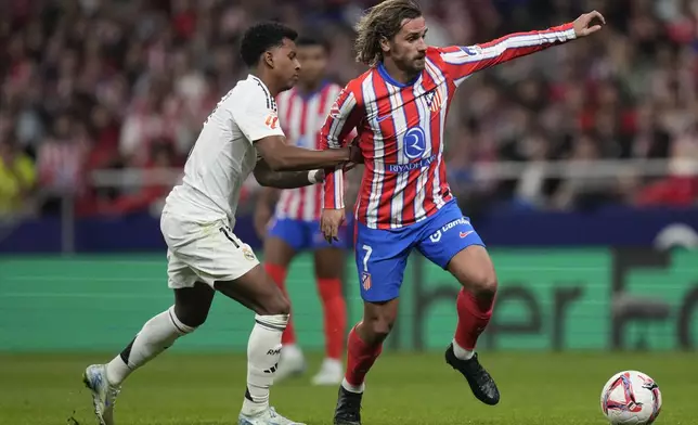 Real Madrid's Rodrygo holds Atletico Madrid's Antoine Griezmann during the La Liga soccer match between Atletico Madrid and Real Madrid at the Metropolitano stadium in Madrid, Spain, Sunday, Sept. 29, 2024. (AP Photo/Bernat Armangue)