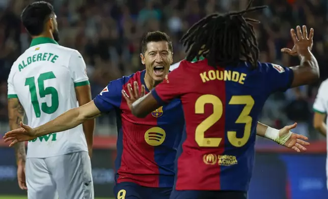 Barcelona's Robert Lewandowski, center, celebrates with Barcelona's Jules Kounde, front, after scoring the opening goal during a Spanish La Liga soccer match between Barcelona and Getafe at the Olympic stadium in Barcelona, Spain, Wednesday, Sept. 25, 2024. (AP Photo/Joan Monfort)