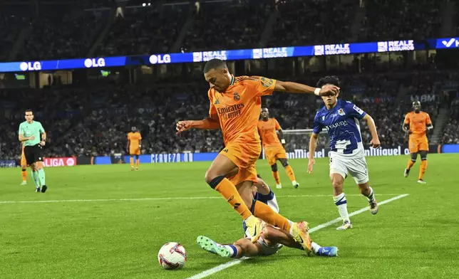 Real Madrid's Kylian Mbappe is tackled by Real Sociedad's Jon Aramburu during a Spanish La Liga soccer match between Real Sociedad and Real Madrid at the Reale Arena in San Sebastian, Spain, Saturday, Sept. 14, 2024. (AP Photo/Miguel Oses)