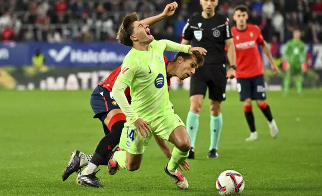 Barcelona's Pablo Torre is tacked by Osasuna's Lucas Torro during a Spanish La Liga soccer match between Osasuna and Barcelona at El Sadar stadium in Pamplona, Spain, Saturday, Sept. 28, 2024. (AP Photo/Miguel Oses)