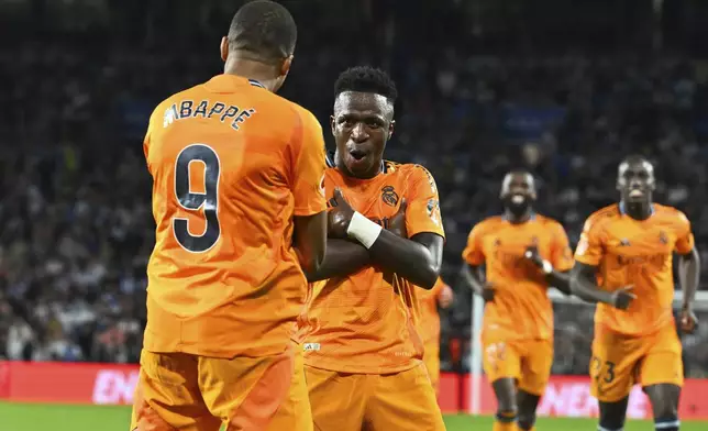 Real Madrid's Kylian Mbappe celebrates with Vinicius Junior, 2nd left, after scoring his side's second goal from a penalty kick during a Spanish La Liga soccer match between Real Sociedad and Real Madrid at the Reale Arena in San Sebastian, Spain, Saturday, Sept. 14, 2024. (AP Photo/Miguel Oses)