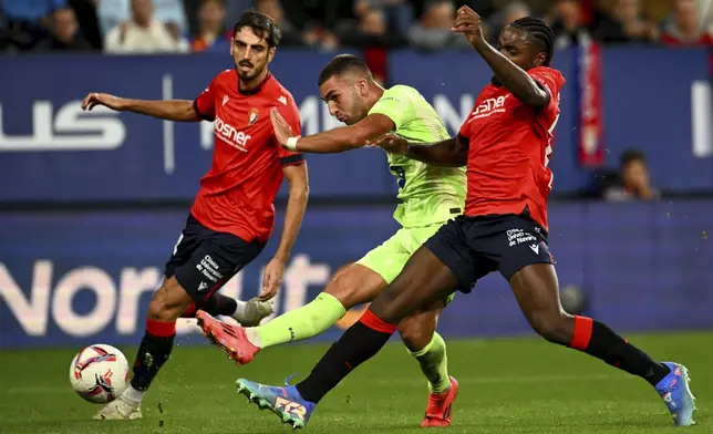 Barcelona's Pau Cubarsi fights for the ball against Osasuna's Enzo Boyomo during a Spanish La Liga soccer match between Osasuna and Barcelona at El Sadar stadium in Pamplona, Spain, Saturday, Sept. 28, 2024. (AP Photo/Miguel Oses)