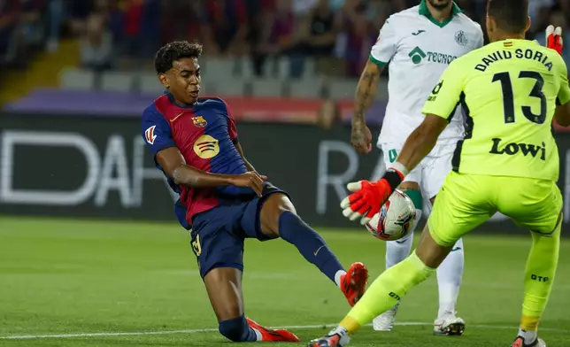 Getafe's goalkeeper David Soria, right, makes a save in front of Barcelona's Lamine Yamal during a Spanish La Liga soccer match between Barcelona and Getafe at the Olympic stadium in Barcelona, Spain, Wednesday, Sept. 25, 2024. (AP Photo/Joan Monfort)