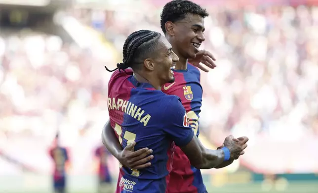 Barcelona's Raphinha, front, is congratulated by Lamine Yamal after scoring his side's 5th goal during the Spanish La Liga soccer match between FC Barcelona and Valladolid at the Olympic stadium in Barcelona, Spain, Saturday, Aug. 31, 2024. (AP Photo/Joan Monfort)