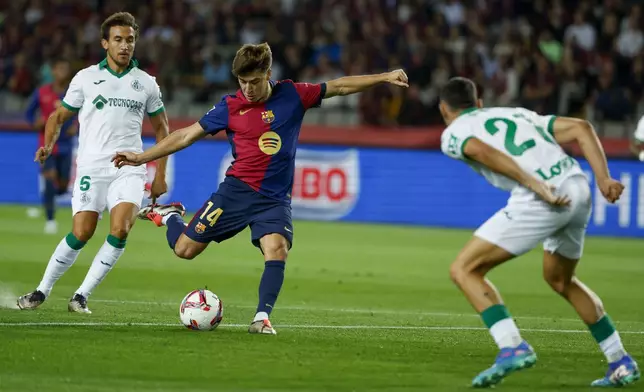 Getafe's Juan Iglesias, right, tries to block a shot from Barcelona's Pablo Torre during a Spanish La Liga soccer match between Barcelona and Getafe at the Olympic stadium in Barcelona, Spain, Wednesday, Sept. 25, 2024. (AP Photo/Joan Monfort)