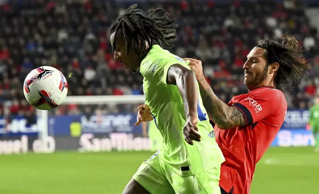 Barcelona's Alejandro Balde fights for the ball against Osasuna's Juan Cruz during a Spanish La Liga soccer match between Osasuna and Barcelona at El Sadar stadium in Pamplona, Spain, Saturday, Sept. 28, 2024. (AP Photo/Miguel Oses)