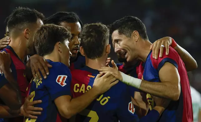 Barcelona's Robert Lewandowski, right, celebrates with teammates after scoring the opening goal during a Spanish La Liga soccer match between Barcelona and Getafe at the Olympic stadium in Barcelona, Spain, Wednesday, Sept. 25, 2024. (AP Photo/Joan Monfort)