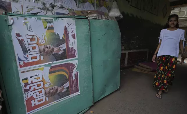 A woman walks past old election posters of presidential candidate Ranil Wickremesinghe at a street in Colombo, Sri Lanka, Sunday, Sept. 22, 2024.(AP Photo/Rajesh Kumar Singh)