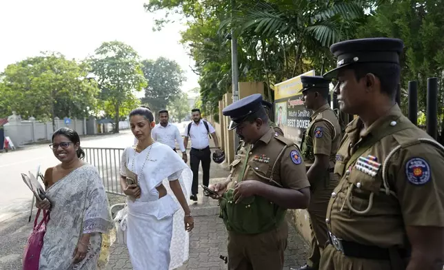 Women election officials walk past security personnel outside a distribution center before collecting polling materials for the upcoming presidential election, in Colombo, Sri Lanka, Friday, Sept. 20, 2024. (AP Photo/Eranga Jayawardena)