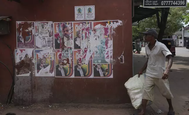 A man walks past old election posters of presidential candidates Anura Kumara Dissanayake and Ranil Wickremesinghe at a street in Colombo, Sri Lanka, Sunday, Sept. 22, 2024.(AP Photo/Rajesh Kumar Singh)