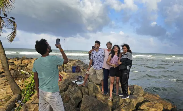 Indian tourists pose for a photograph on a beach in Colombo, Sri Lanka, Tuesday, Sept. 17, 2024. (AP Photo/Rajesh Kumar Singh)