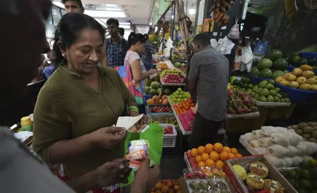 A woman buys fruits from a stall at a local wholesale market, in Colombo, Sri Lanka, Wednesday, Sept. 18, 2024. (AP Photo/Rajesh Kumar Singh)